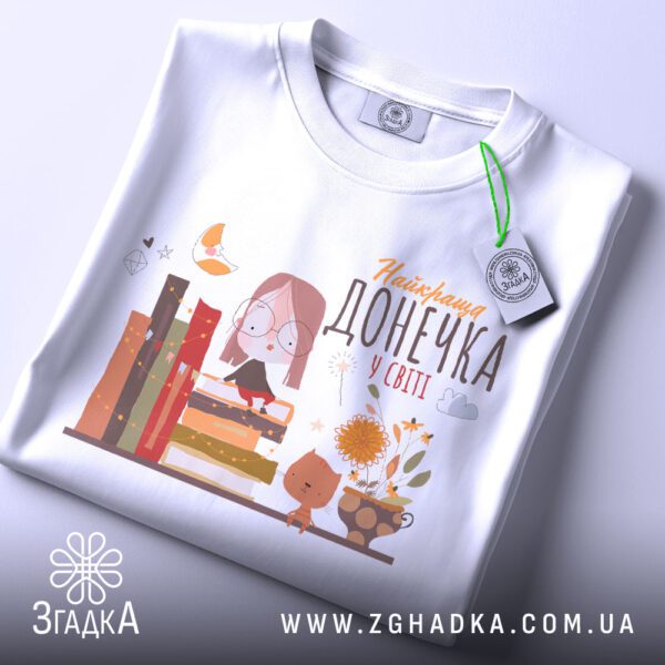 Футболка Найкраща Донечка Книголюб - детальний вигляд дівчинки, яка читає на стопці книг.