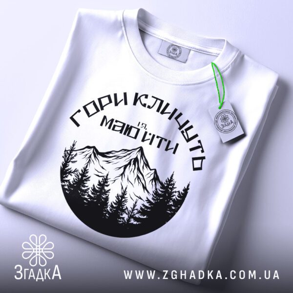 Футболка Гори Кличуть Подарунок: Крупний план на зображення гір та дерев на футболці.
