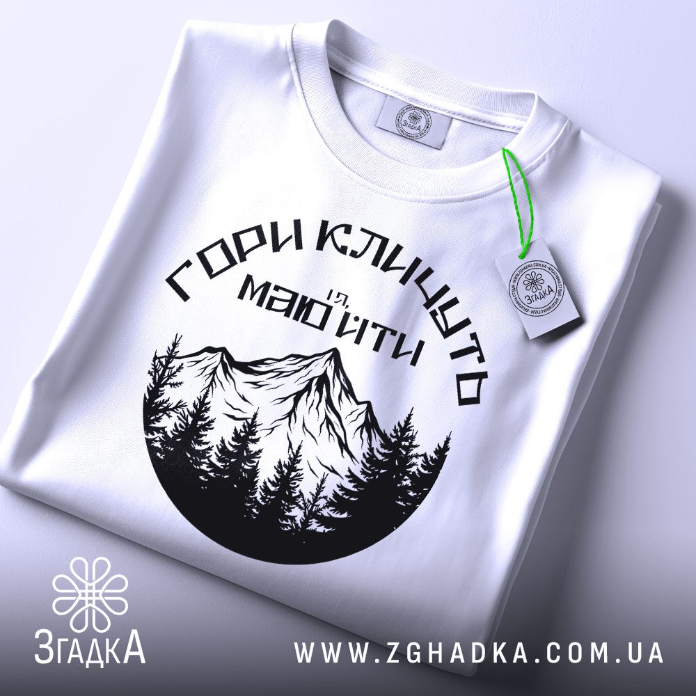 Футболка Гори Кличуть Подарунок: Крупний план на зображення гір та дерев на футболці.