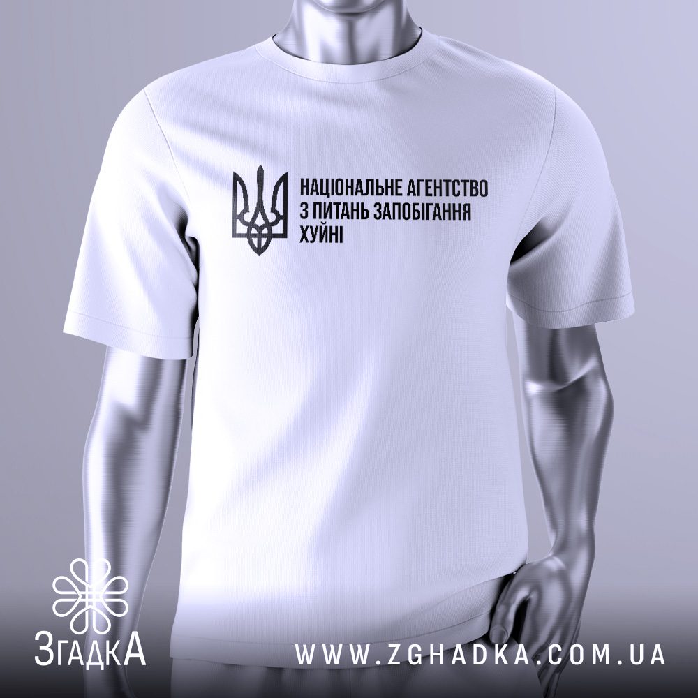 Біла футболка Агентство Запобігання Подарунок на сріблястому манекені, що демонструє принт з написом "НАЦІОНАЛЬНЕ АГЕНТСТВО З ПИТАНЬ ЗАПОБІГАННЯ ХУЙНІ" та українським гербом.