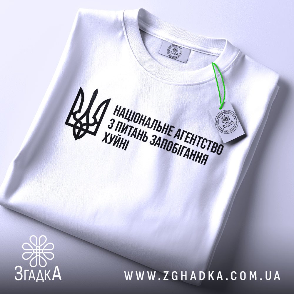 Складена біла футболка Агентство Запобігання Подарунок з гумористичним принтом та етикеткою "ЗГАДКА".