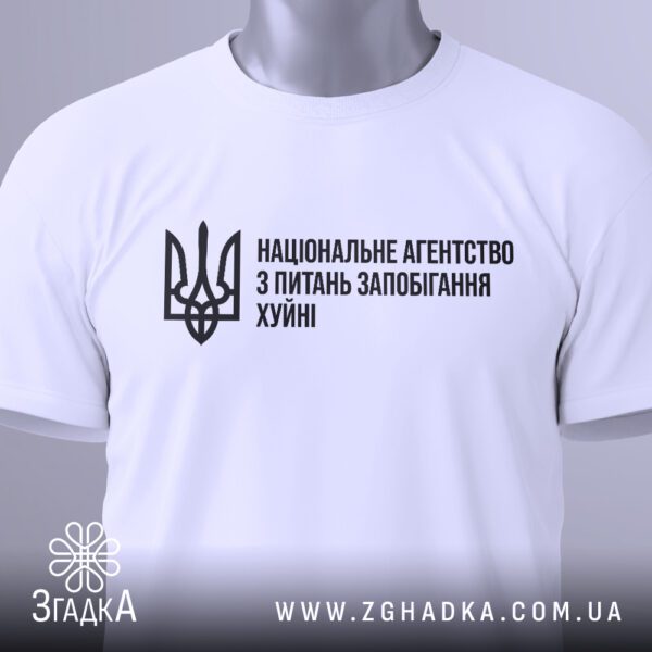 Фронтальний вигляд білої футболки Агентство Запобігання Подарунок на манекені, крупний план принта.