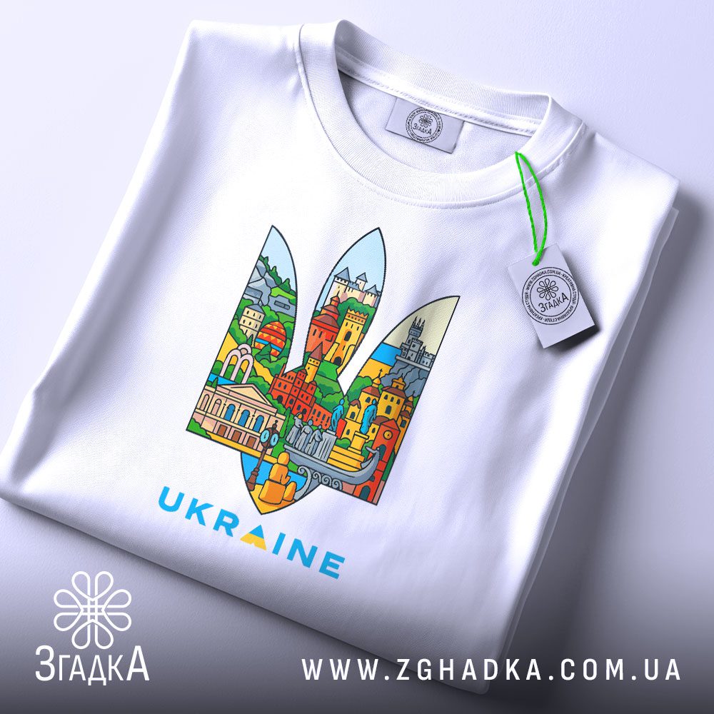 Складена біла футболка Герб України місто з принтом Тризуба, наповненого архітектурними елементами, з етикеткою згадка.