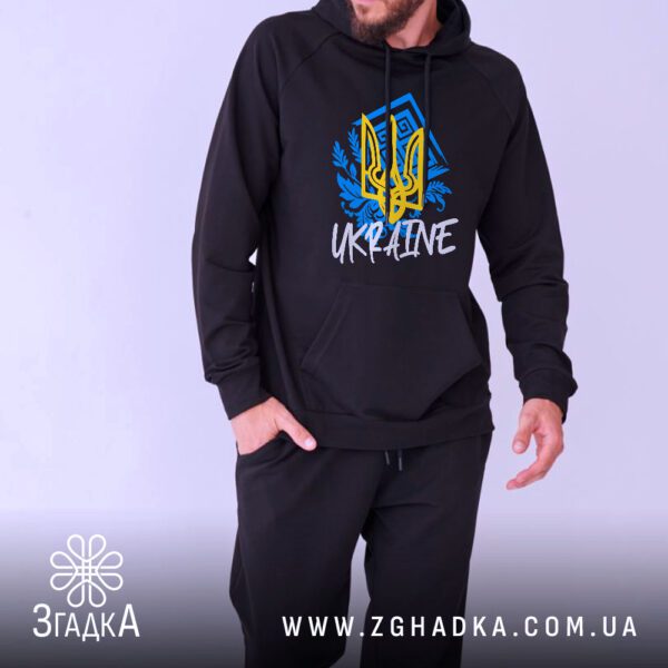 Чоловік у чорному худі з українським гербом і написом — погляд збоку