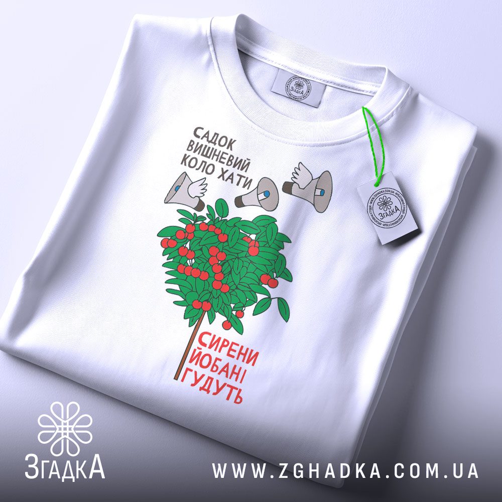 Складена біла футболка з принтом "Садок вишневий коло хати — сирени йобані гудуть" та етикеткою "Згадка".