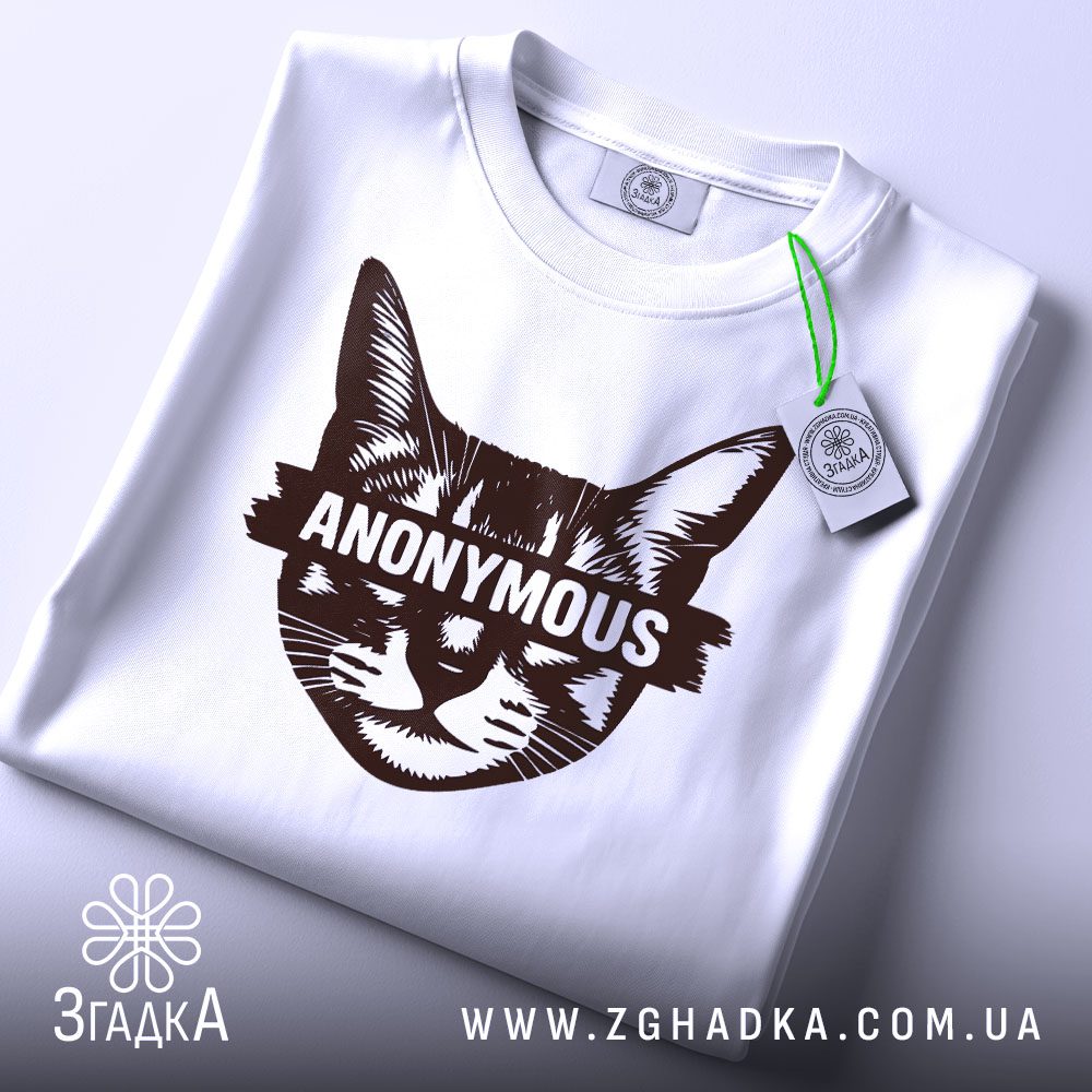 Складена біла футболка з принтом "анонімний стиль кота" та етикеткою "Згадка".