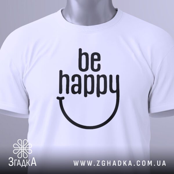 Крупний план принта "be happy" на білій футболці, що детально показує стилізовану усмішку та текст.