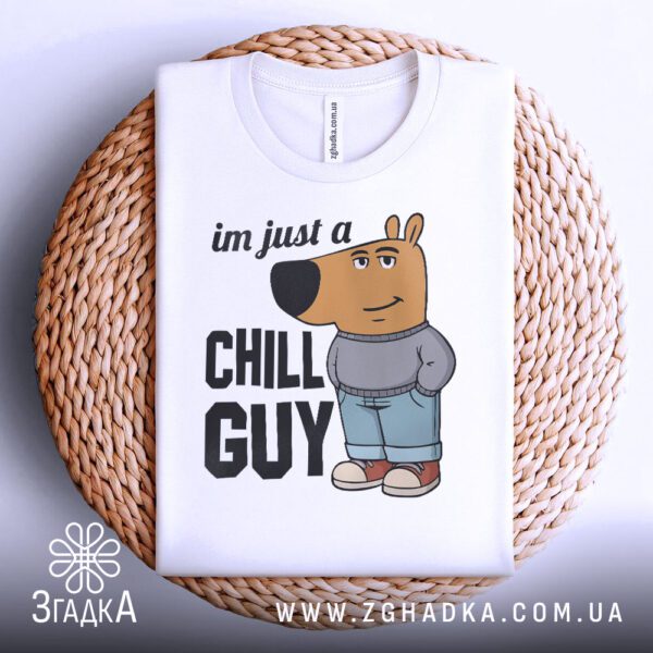 Біла футболка з принтом "chill guy стиль", акуратно складена на круглій дерев'яній поверхні.