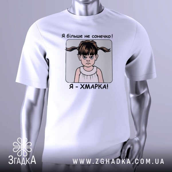 Біла футболка з графічним принтом у центрі. На принті зображено стилізовану дівчинку з розпущеним волоссям і сердитим виразом обличчя. Над головою дівчинки хмарка з блискавкою. Зверху і знизу від дівчинки напис: "Я БІЛЬШЕ НЕ СОНЕЧКО — Я ХМАРКА!". Футболка на сірому манекені.