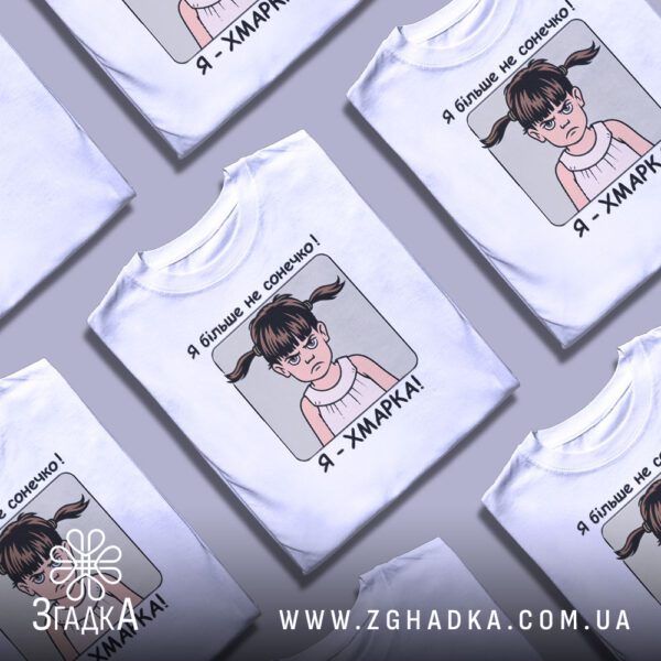 Кілька білих футболок з принтом "дівчинка я хмарка", складені стопкою або розкладені поруч на світлому фоні.