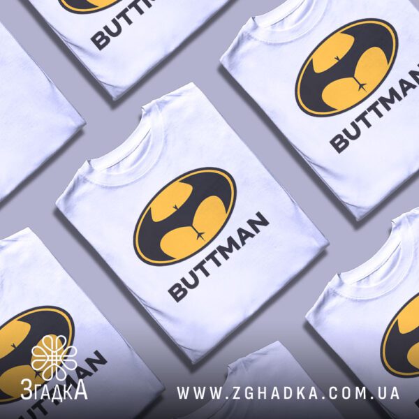 Кілька чорних футболок з принтом "BUTTMAN", складені стопкою або розкладені поруч на світлому фоні.