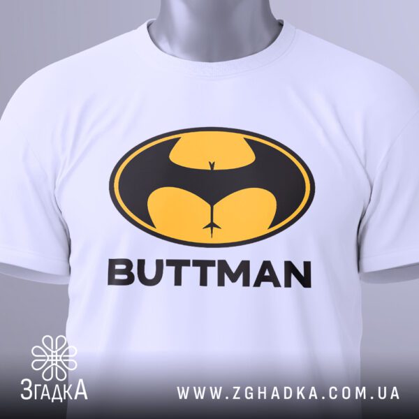 Крупний план принта "BUTTMAN" на чорній футболці, що детально показує текст та графічне зображення.