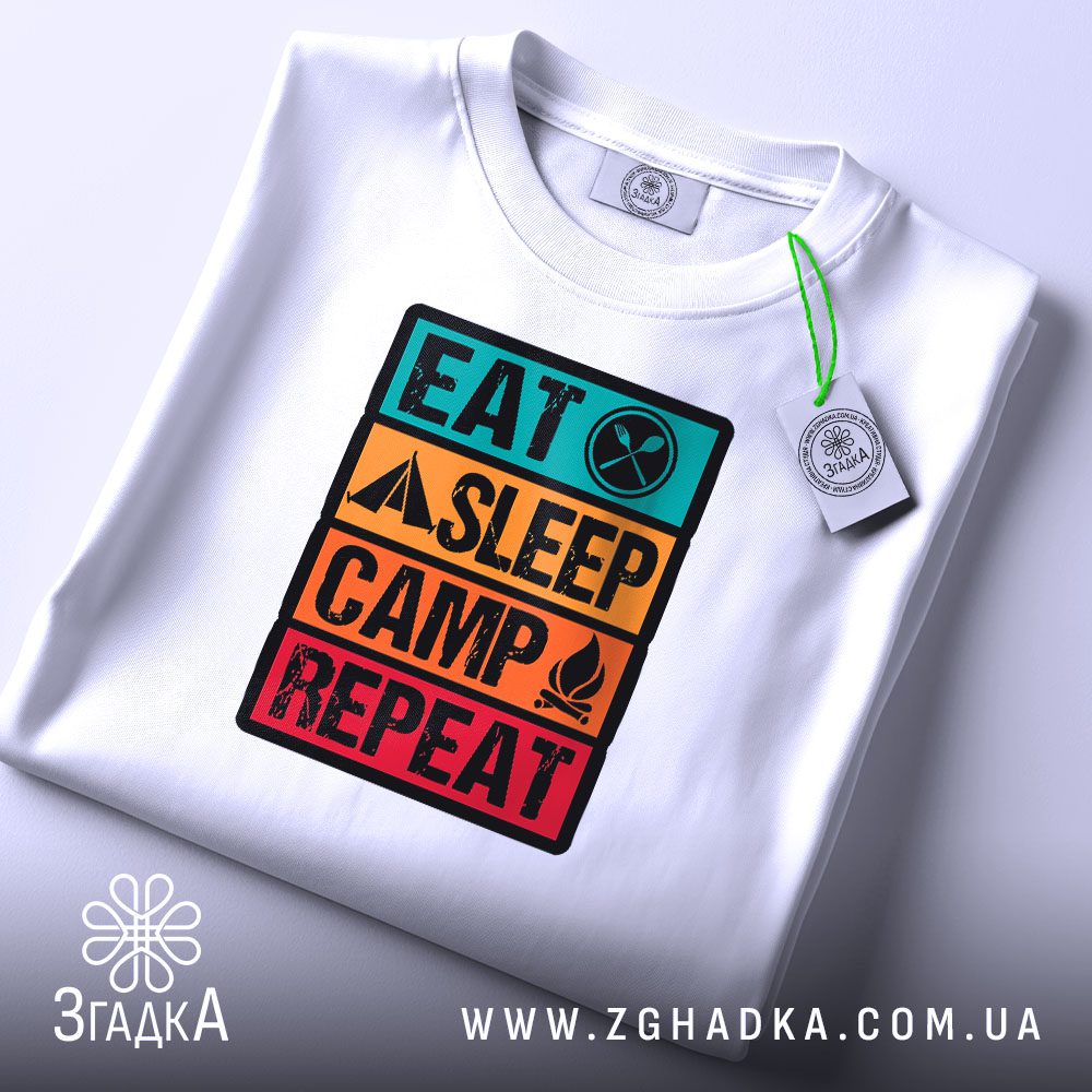 Складена біла футболка з принтом "Eat Sleep Camp Repeat" та етикеткою "Згадка".