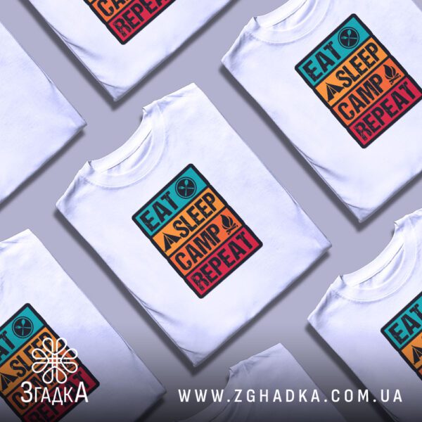 Кілька білих футболок з принтом "Eat Sleep Camp Repeat", складені стопкою або розкладені поруч на світлому фоні.