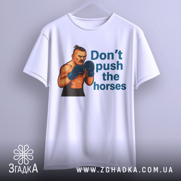 Біла футболка з принтом "don't push horses", що висить на білих плічках, демонструючи дизайн.