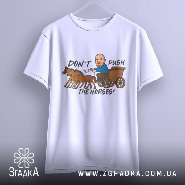 Біла футболка з принтом "don't push карикатура", що висить на білих плічках, демонструючи дизайн.