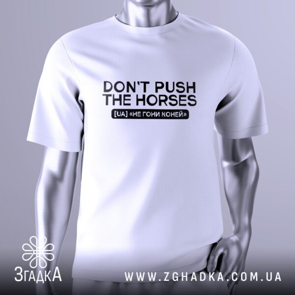 Біла футболка з чорним текстовим принтом у центрі. Напис "DON’T PUSH THE HORSES" виконаний великими літерами, під ним зображення конячого черепа з крилами, що додає іронії та стилістики. Футболка на сірому манекені.