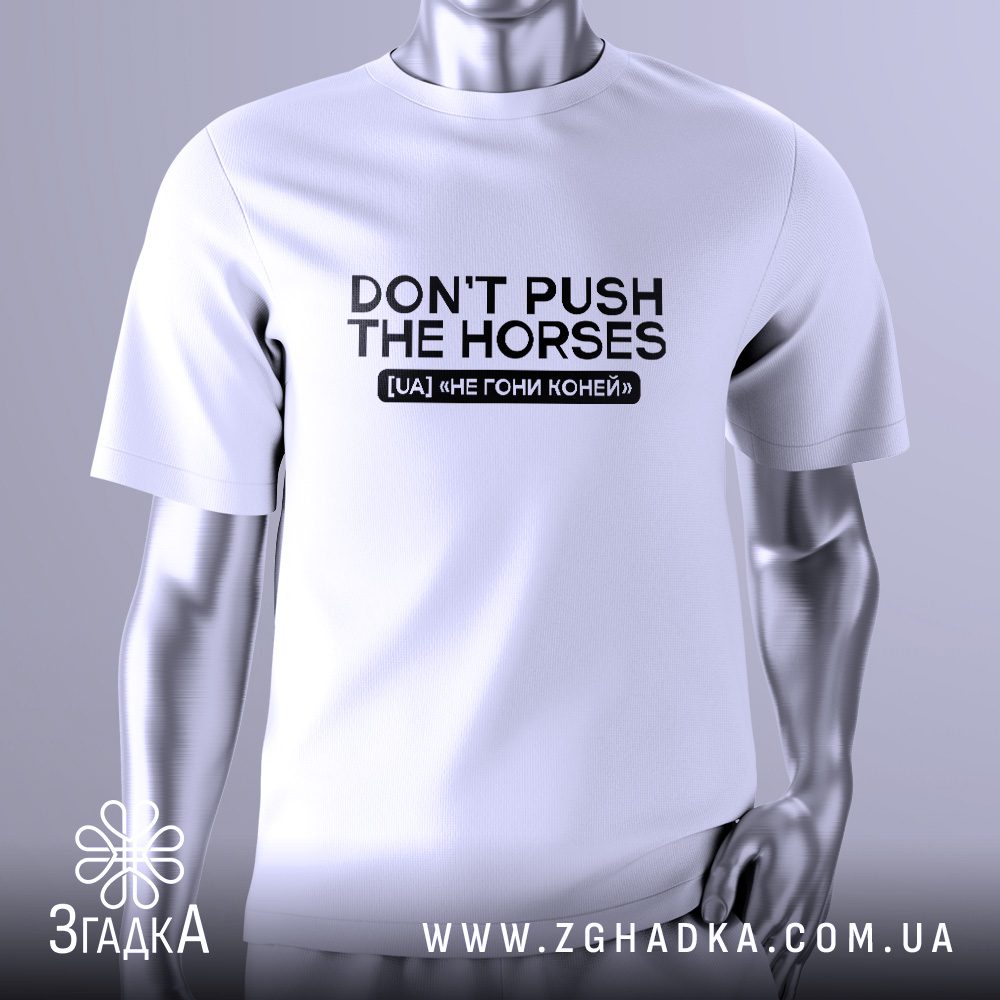 Біла футболка з чорним текстовим принтом у центрі. Напис "DON’T PUSH THE HORSES" виконаний великими літерами, під ним зображення конячого черепа з крилами, що додає іронії та стилістики. Футболка на сірому манекені.