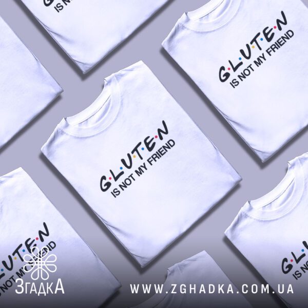 Кілька білих футболок з принтом "Gluten is not my friend", складені одна на одну або розкладені поруч на сірому фоні.