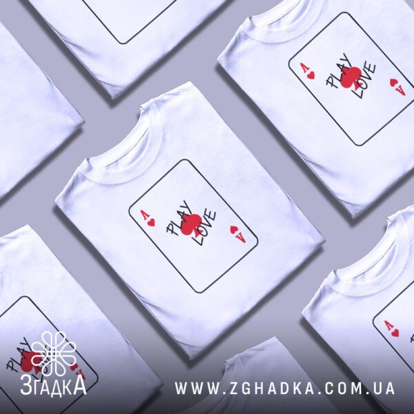Кілька білих футболок з принтом "гра у кохання", складені стопкою або розкладені поруч на світлому фоні.