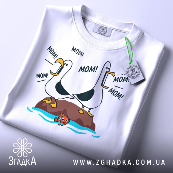 Складена біла футболка з принтом чайок "MOM!" та етикеткою "Згадка".