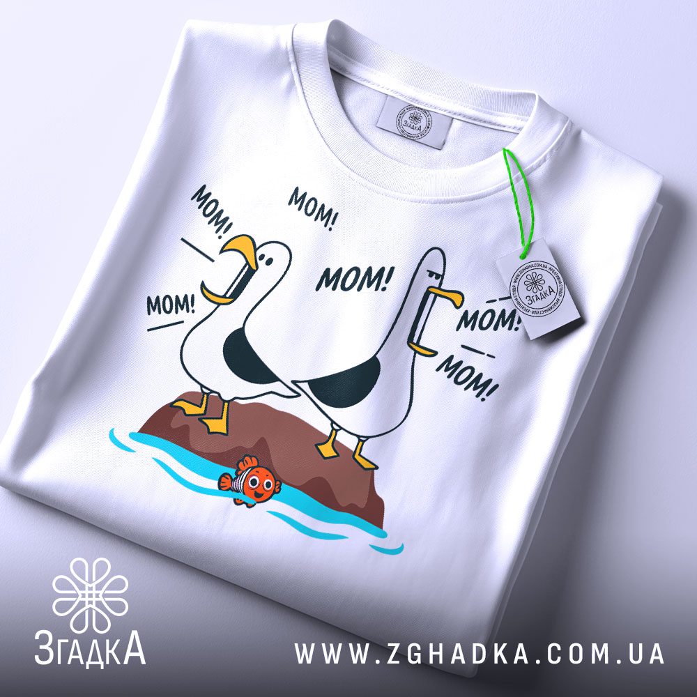 Складена біла футболка з принтом чайок "MOM!" та етикеткою "Згадка".