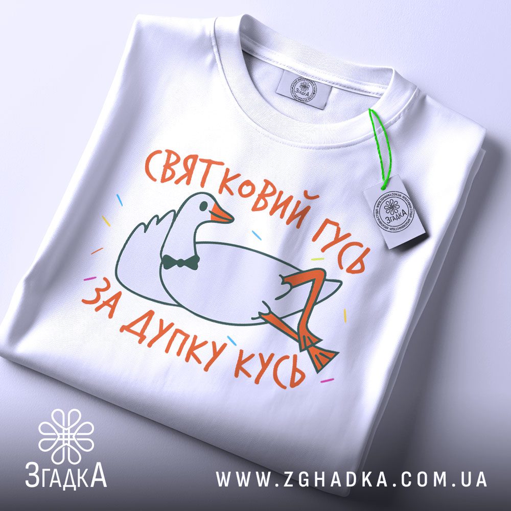 Складена біла футболка з принтом "гусь дупку кусь" та етикеткою "Згадка".