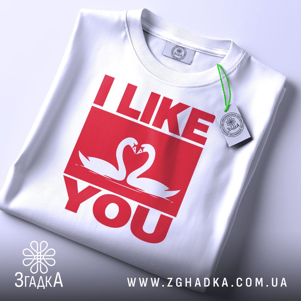 Складена біла футболка з принтом "I LIKE YOU" та етикеткою "Згадка".
