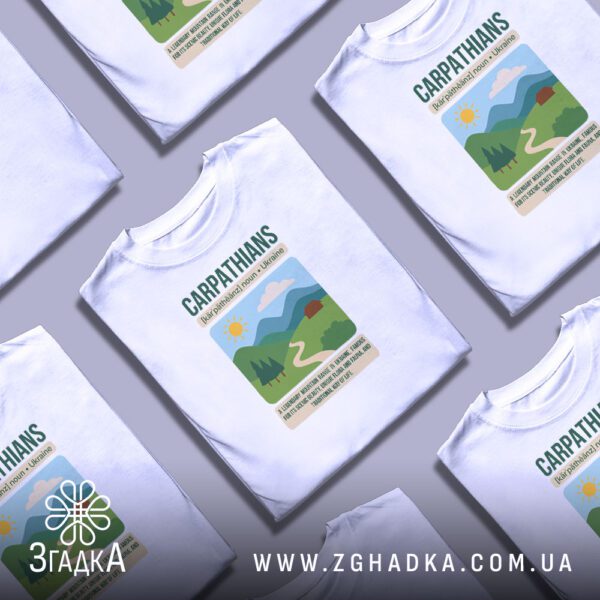 Кілька білих футболок з принтом "краса Карпатських гір", складені стопкою або розкладені поруч на світлому фоні.