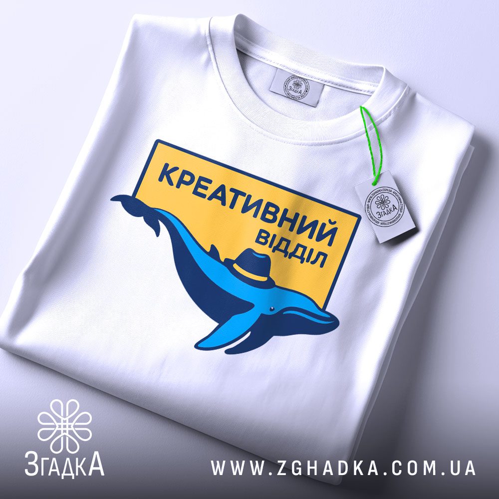 Складена біла футболка з принтом "креативний відділ стиль" та етикеткою "Згадка".