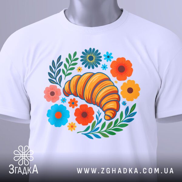 Крупний план графічного принта круасана та квітів на білій футболці.