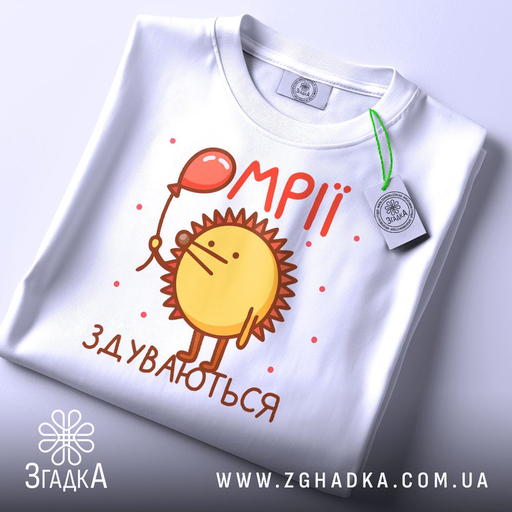 Складена біла футболка з принтом "мрії здуваються їжак" та етикеткою "Згадка".