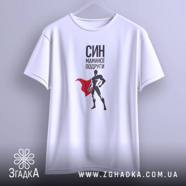 Біла футболка з принтом "СИН МАМИНОЇ ПОДРУГИ", що висить на білих плічках, демонструючи принт повністю.
