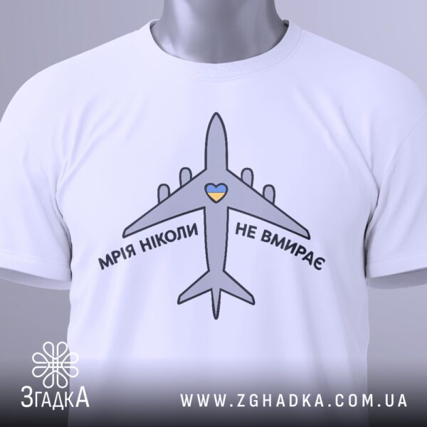 Крупний план принта "мрія не вмирає" на білій футболці, що детально показує зображення літака та тексту.