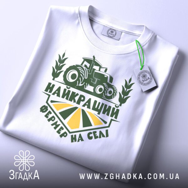 Складена біла футболка Найкращий Фермер з яскравим принтом та етикеткою згадка.
