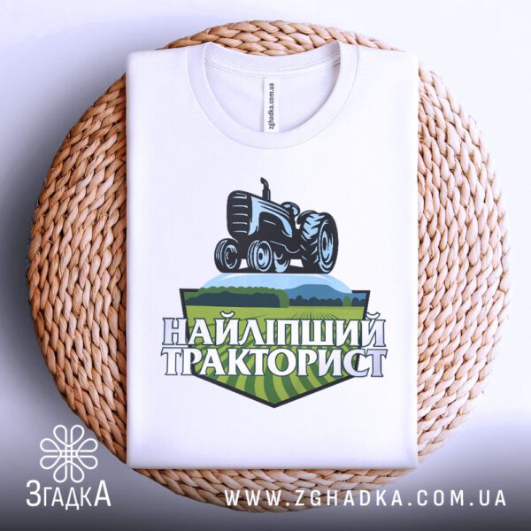 Фронтальний вигляд білої футболки Найліпший Тракторист на манекені, крупний план принта.