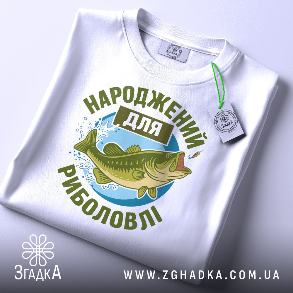 Складена біла футболка з принтом "Народжений для риболовлі" та етикеткою "Згадка".
