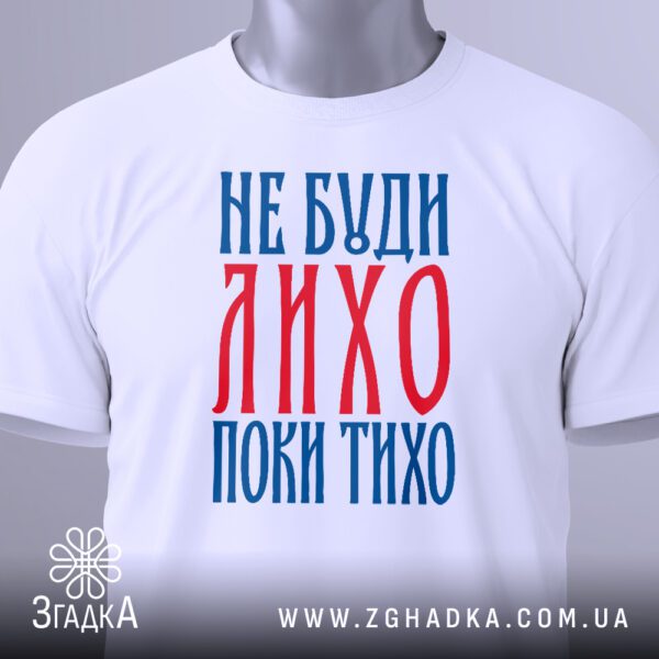 Крупний план принта "не буди лихо" на білій футболці, що детально показує текст українського вислову.