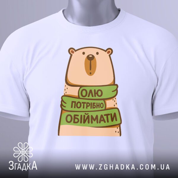 Крупний план принта "Олю потрібно обіймати" на білій футболці, що детально показує ведмедика та напис.