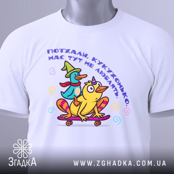 Крупний план принта "поїхали кукухонько" на білій футболці, що детально показує качку, кукуху на скейті та напис.