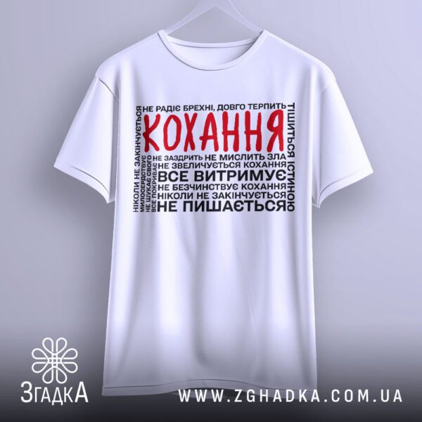 Біла футболка з принтом "про силу кохання", що висить на білих плічках, демонструючи дизайн.