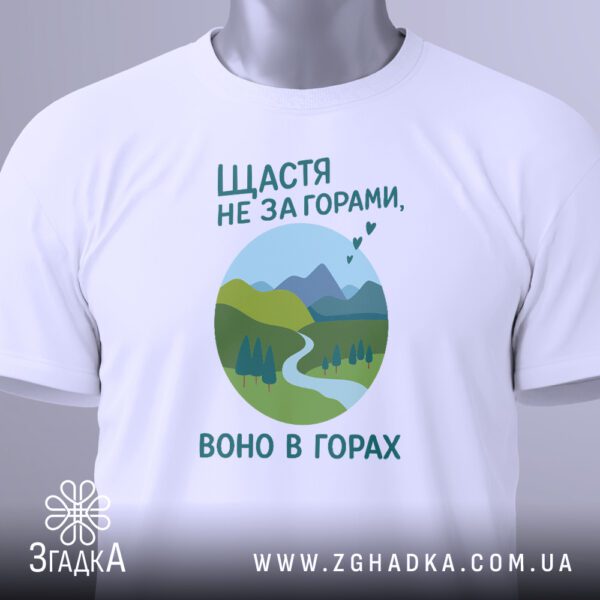 Крупний план принта "щастя в горах" на білій футболці, що детально показує гірський пейзаж та текст.