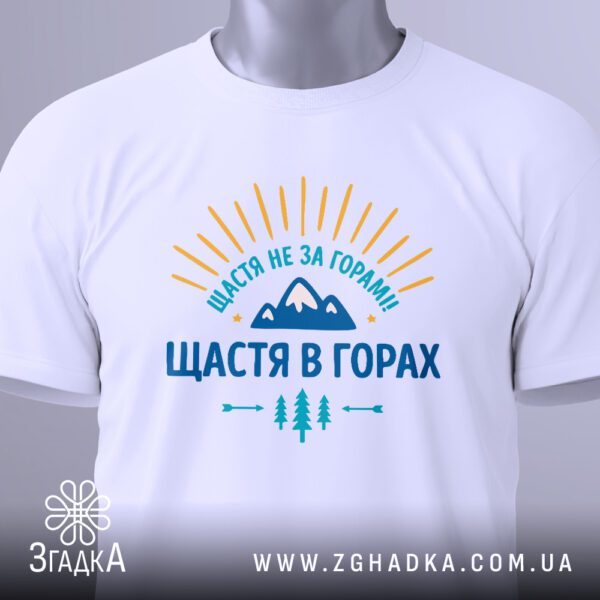 Крупний план принта "щастя в горах" на білій футболці, що детально показує текст та графічні елементи.
