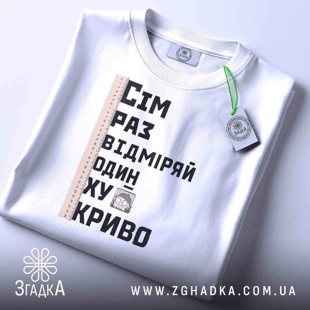 Складена біла футболка з принтом "сім раз відміряй" та етикеткою "Згадка".