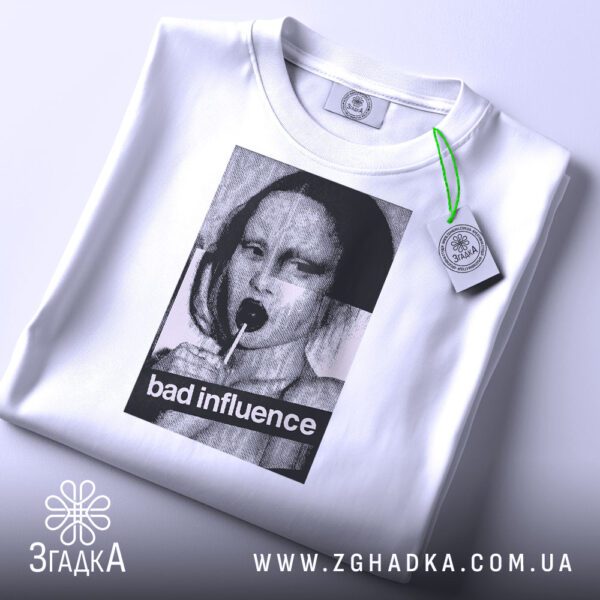 Складена біла футболка з принтом "bad influence" та етикеткою "Згадка".