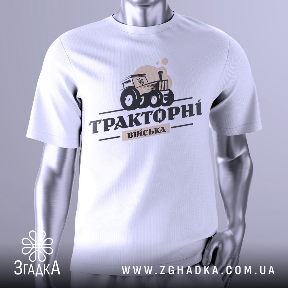 Біла футболка Тракторні Війська на сріблястому манекені, що демонструє гумористичний принт трактора, який тягне танк.