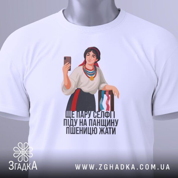 Крупний план принта "український селфі гумор" на білій футболці, що детально показує дівчину, телефон та текст.