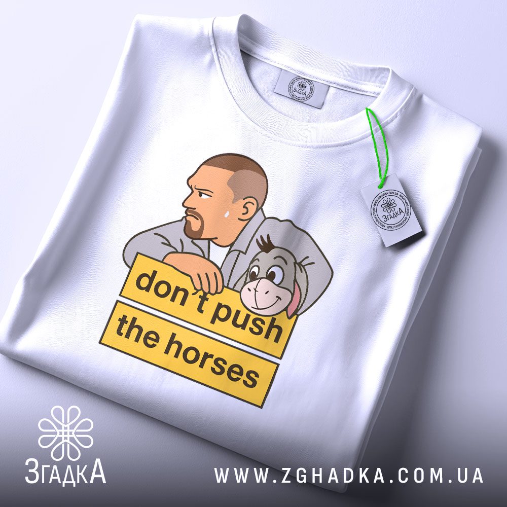 Складена біла футболка з принтом "усик з осликом" та етикеткою "Згадка".