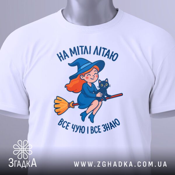 Крупний план графічного принта відьмочки на мітлі на білій футболці.