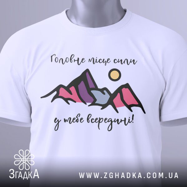 Крупний план принта "внутрішня сила людини" на білій футболці, що детально показує текст та абстрактні гори.